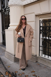 a lady in a black shirt, a pair of brown pants and a long wool coat